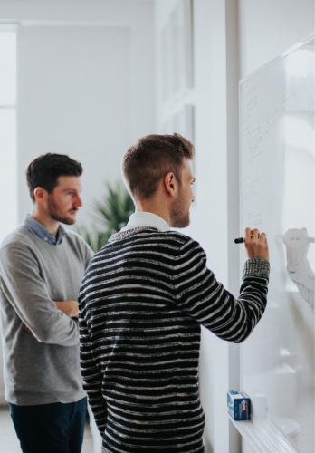 Dois homens concentrados idealizando um projeto novo em frente a um quadro branco